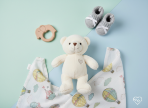 Różnorodne prezenty dla noworodka na pastelowym tle.